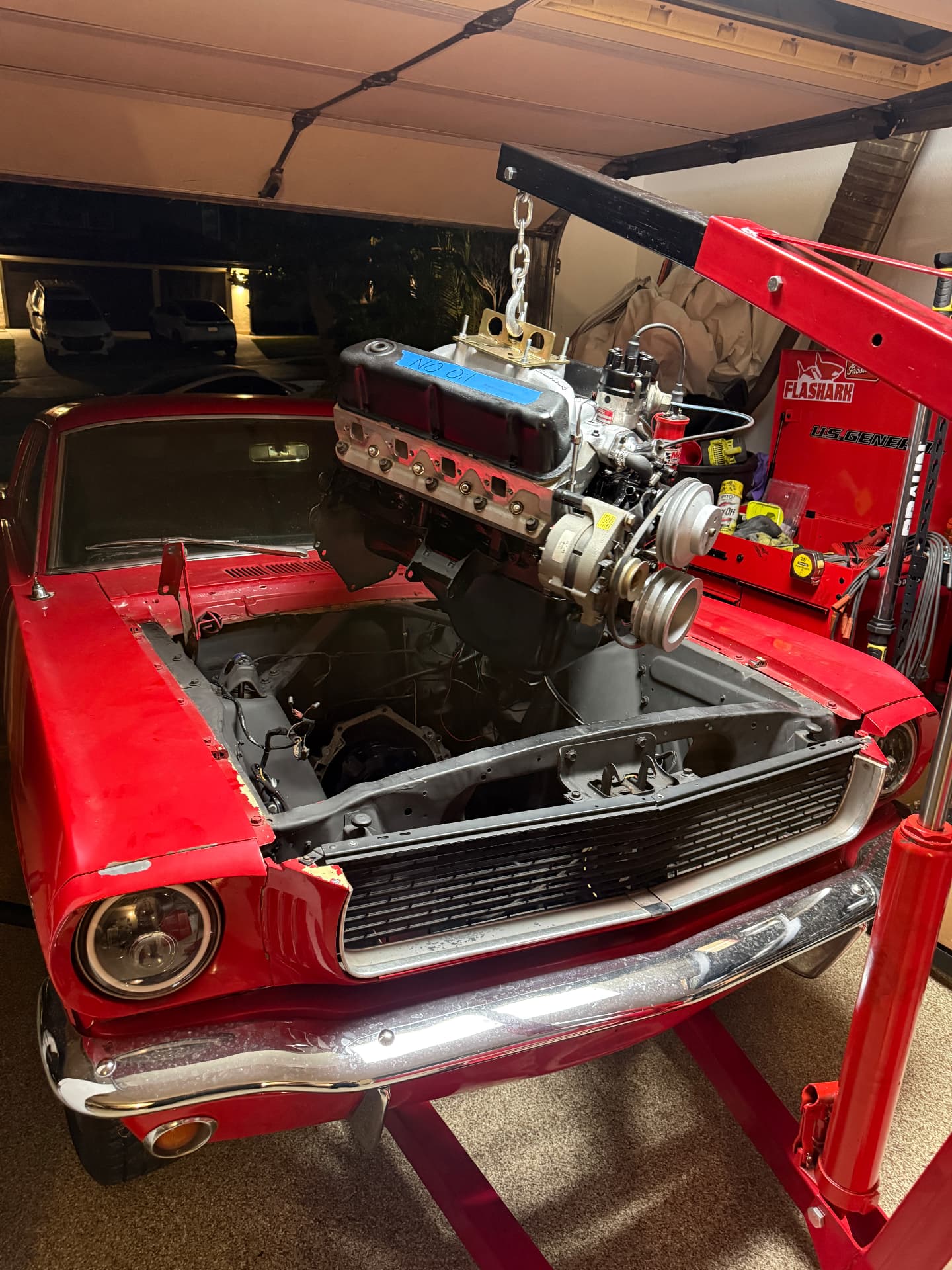 Engine being lowered into the red 1966 Ford Mustang